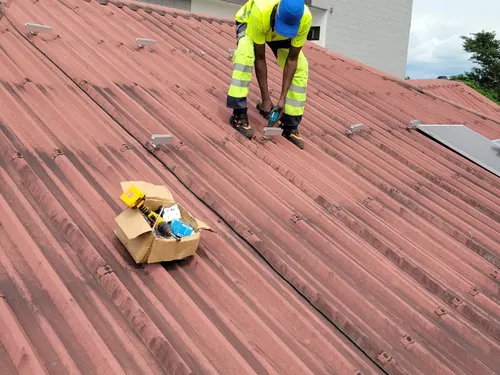 Technician fixing mounting rails on a corrugated metal roof